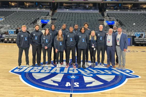 Group photo of Shenandoah University students and staff at midcourt during the Indy Classic in Indianapolis.